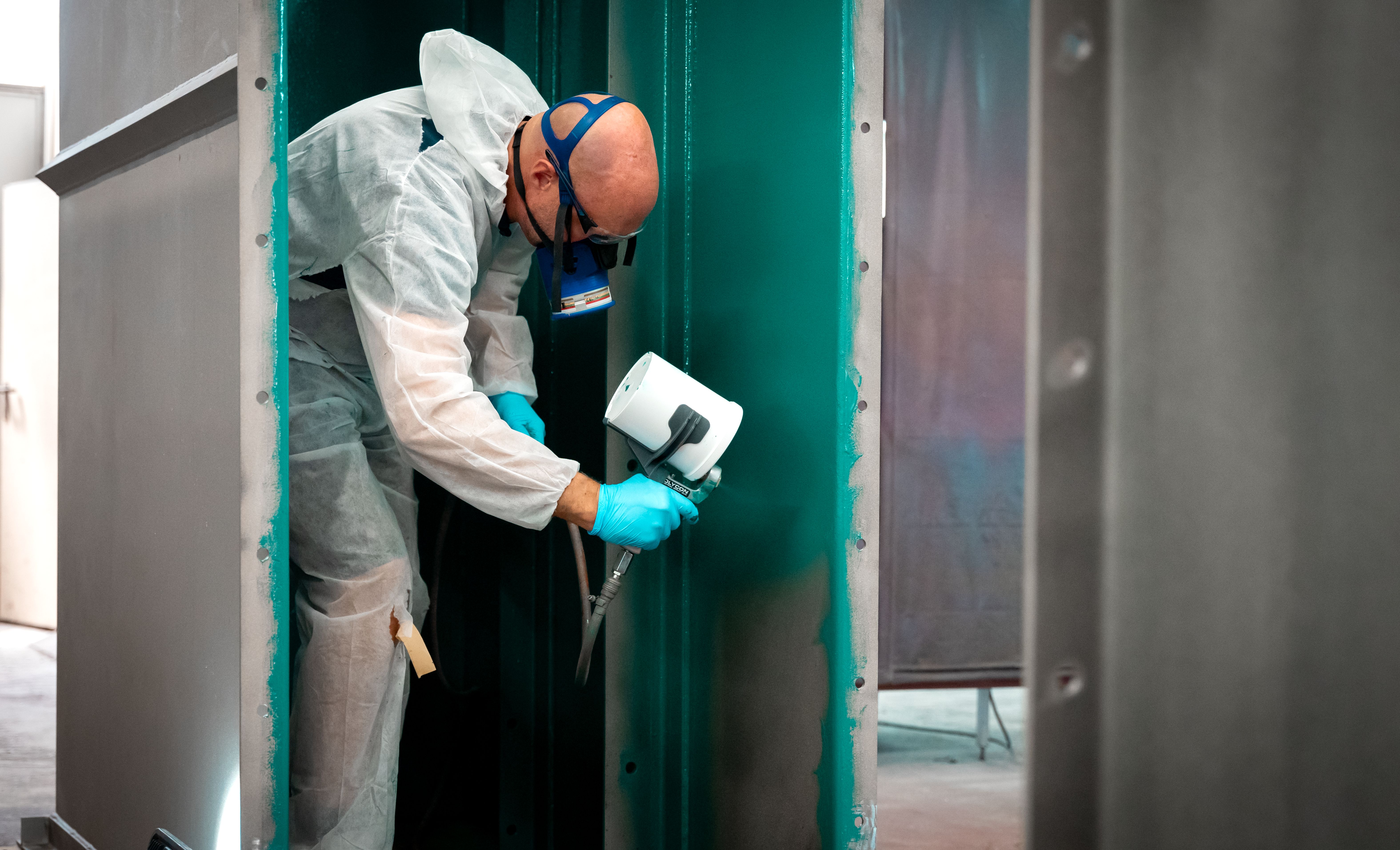 Maske takan bir adam yeşil bir kontrol tabakası püskürtür