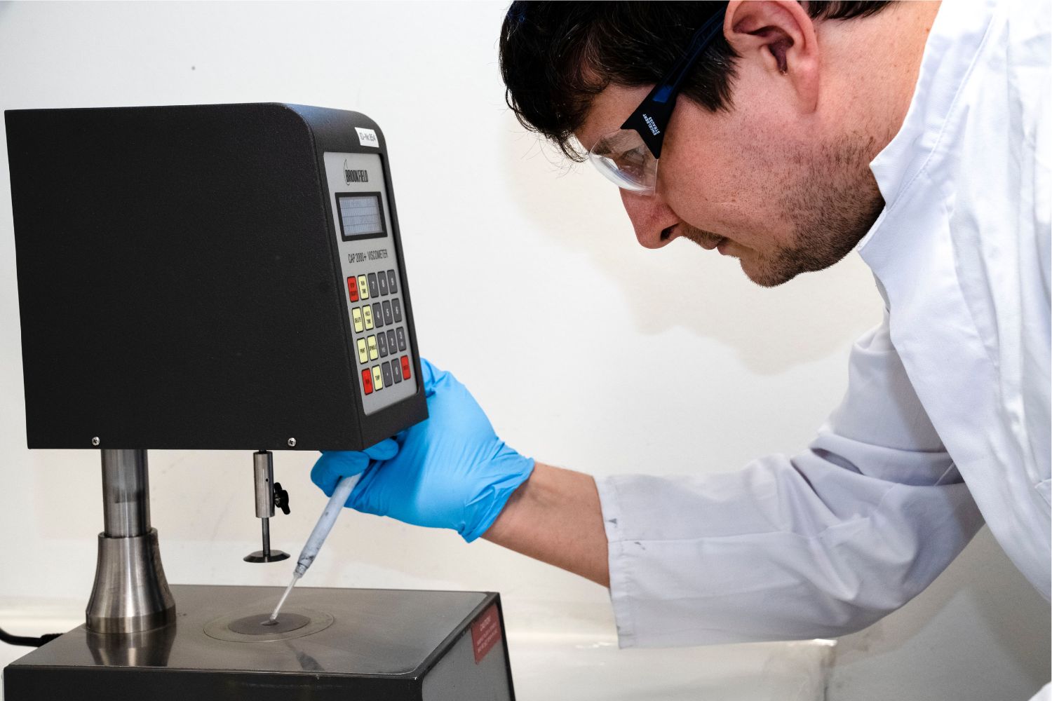 Beyaz önlüklü bir adam pipetten bir şeyi bir yüzeye damlatıyor